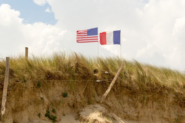 French flag and American flag standing tall for peace at top of dunes, Utah beach, Normandy, France.