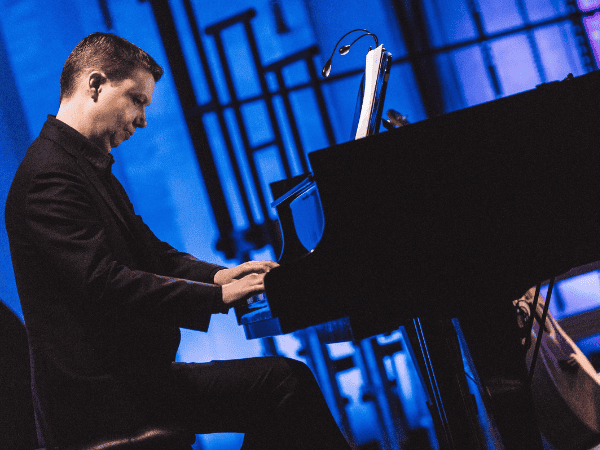Ola Gjeilo playing piano in a concert hall. Photo © Mantas Gudzinevicius
